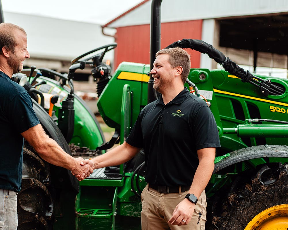 prairie state tractor salesman shakes customers hand